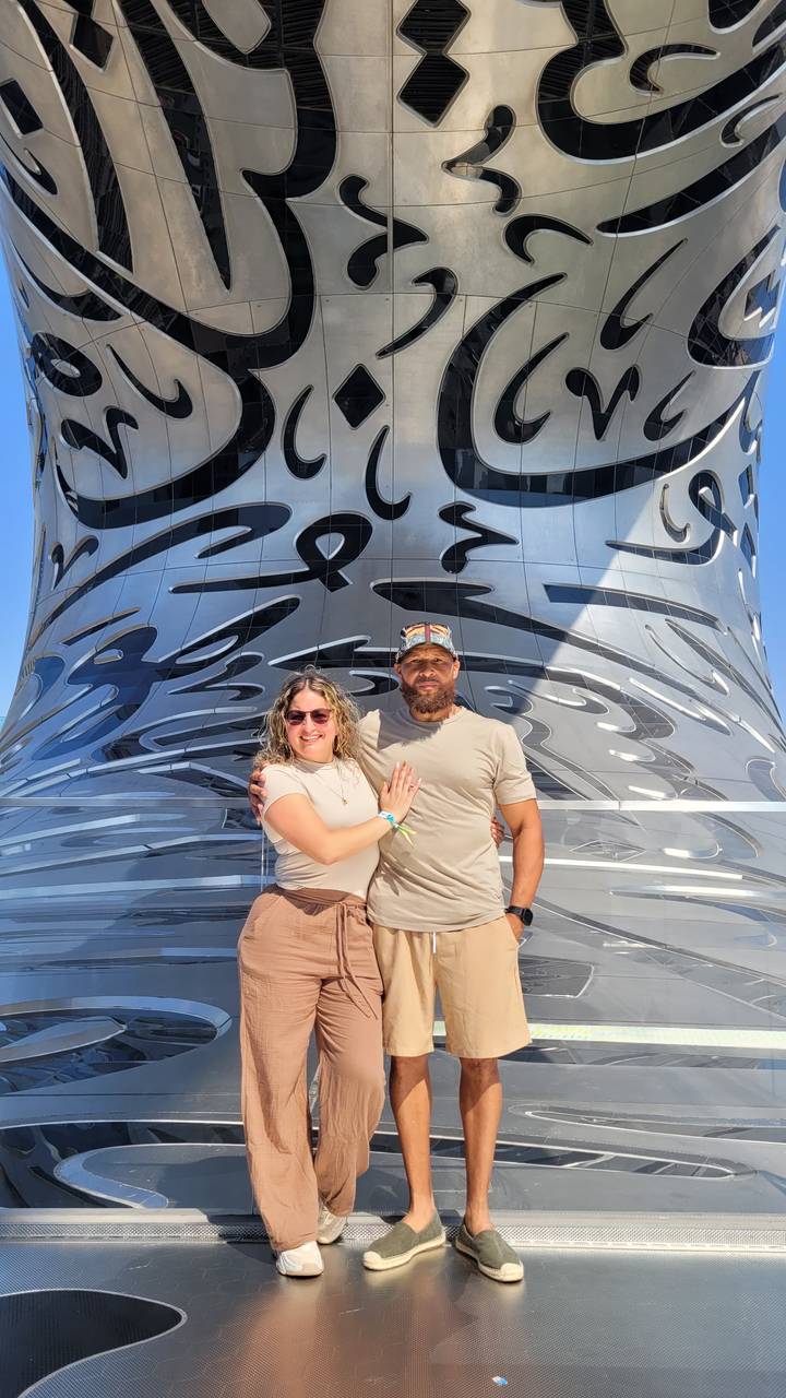 Zwei Personen stehen vor der Fassade mit arabischer Kalligrafie.