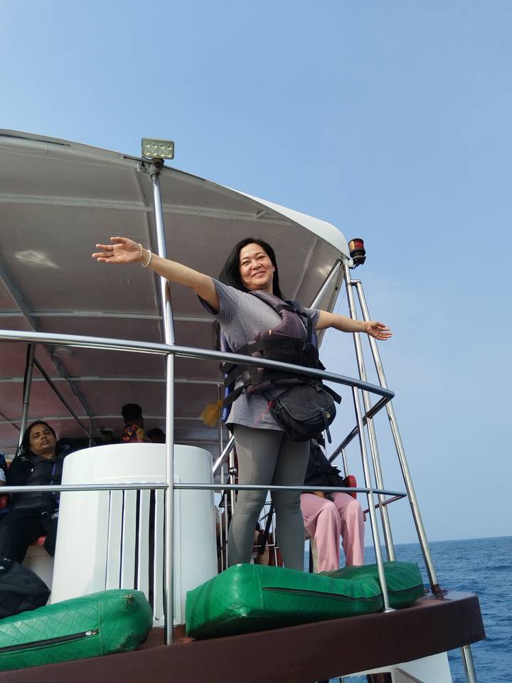 Mujer en un barco extendiendo sus brazos.