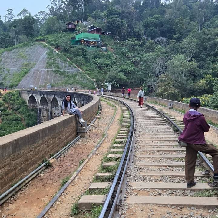 Personas caminando y sentadas en un puente ferroviario.