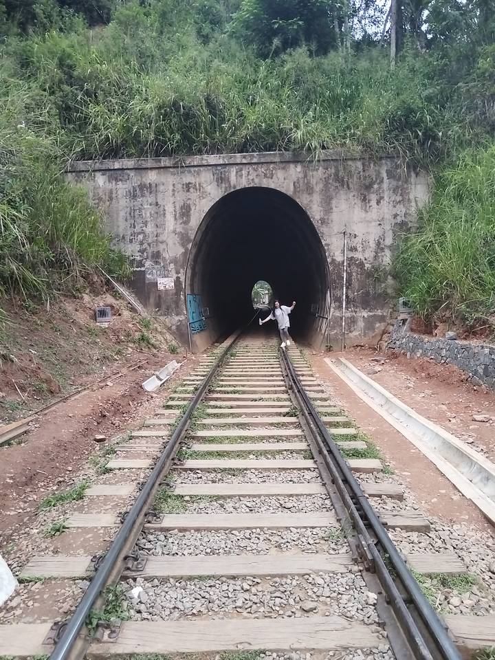 Una mujer en las vías del tren frente a un túnel.