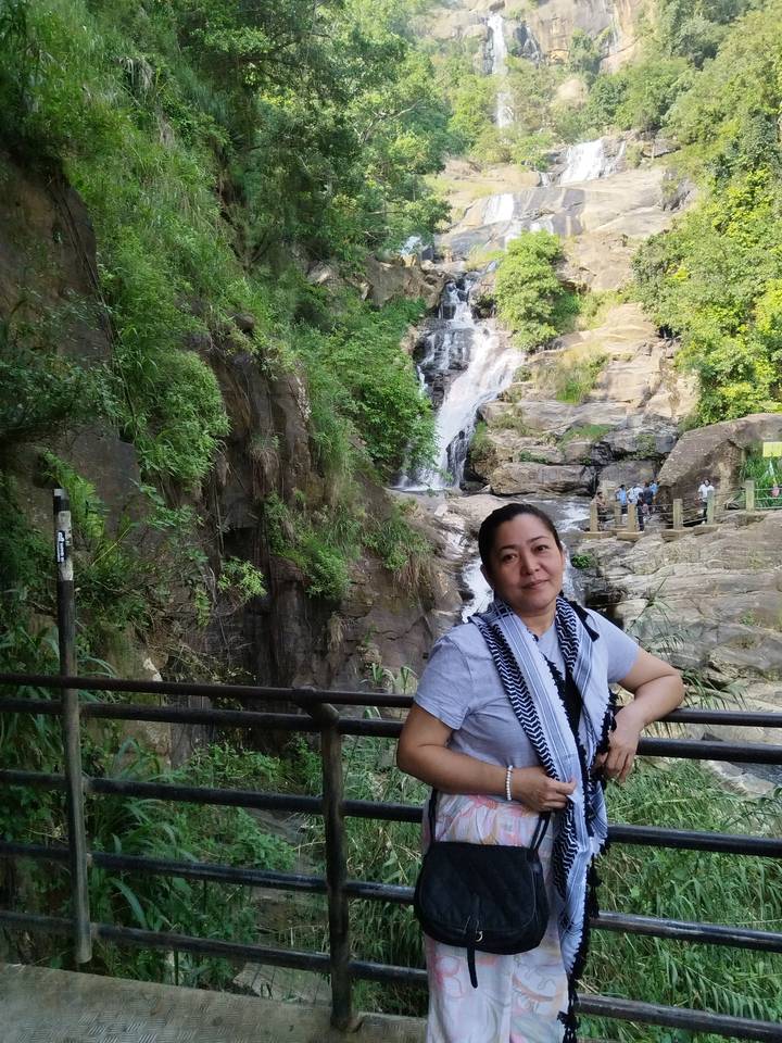Una mujer parada frente a una cascada.