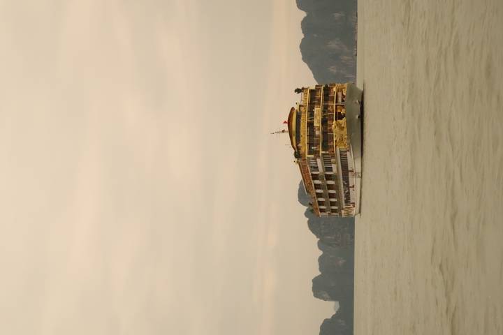 Cruiseschip op kalme wateren met rotsachtig landschap in de verte.