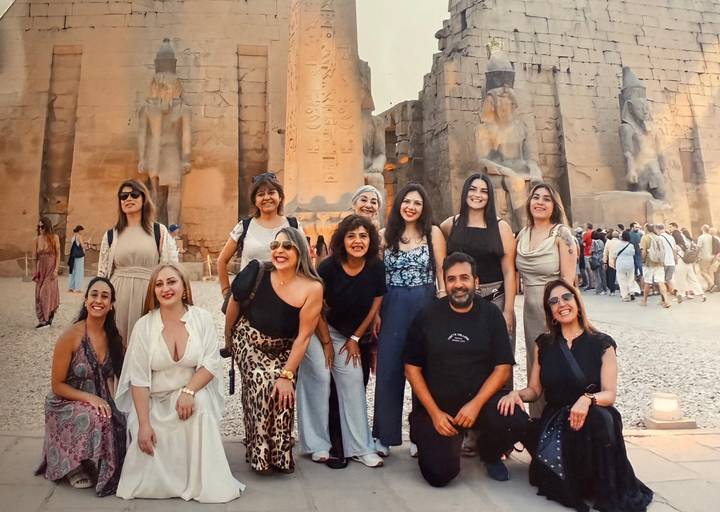 A group of tourists posing in front of ancient Egyptian ruins.