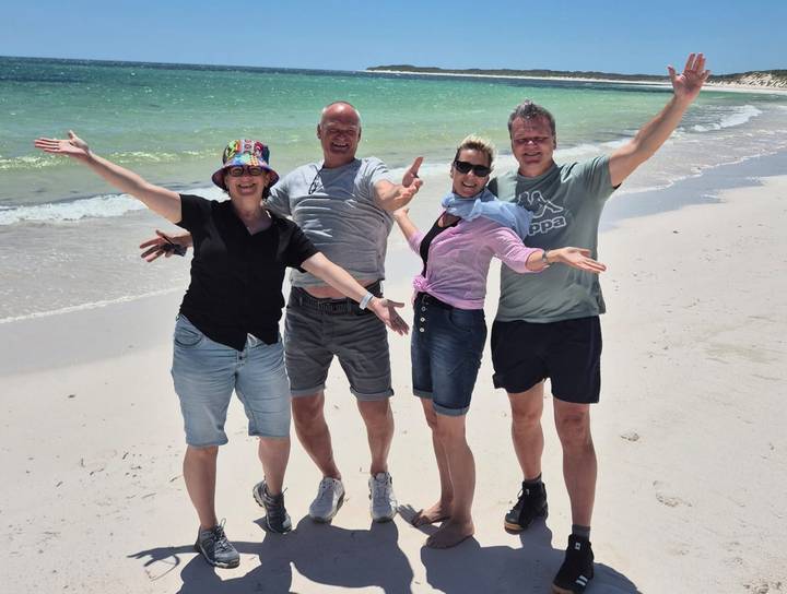 Group of people posing on a beach with the ocean in the background.