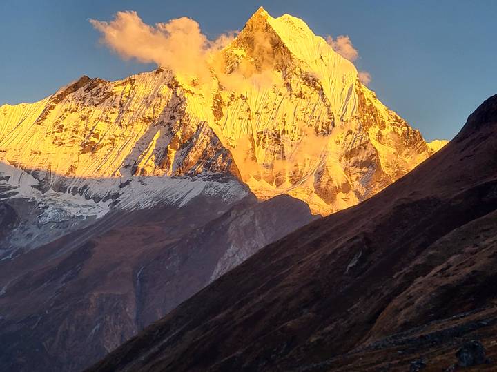 Un sommet de montagne enneigé baigné de lumière dorée.