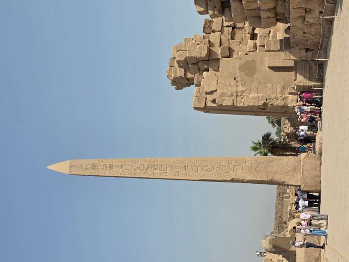 Des touristes visitant un site antique avec un obélisque.