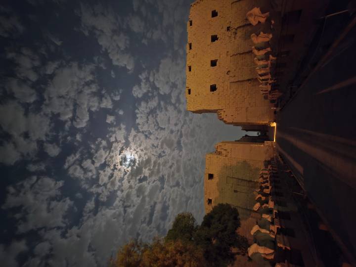 Ruines antiques sous un ciel nocturne nuageux avec clair de lune.