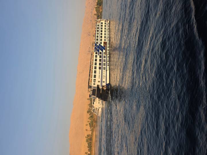 Des bateaux de croisière sur la rivière avec un arrière-plan désertique.