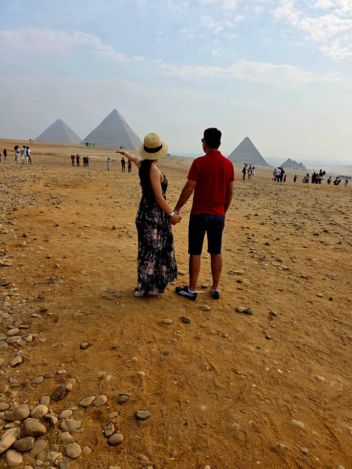 Couple dans le désert avec une pyramide en arrière-plan.