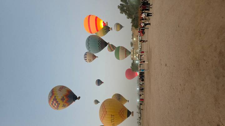 Des montgolfières dans le ciel avec des gens qui regardent d'en bas.