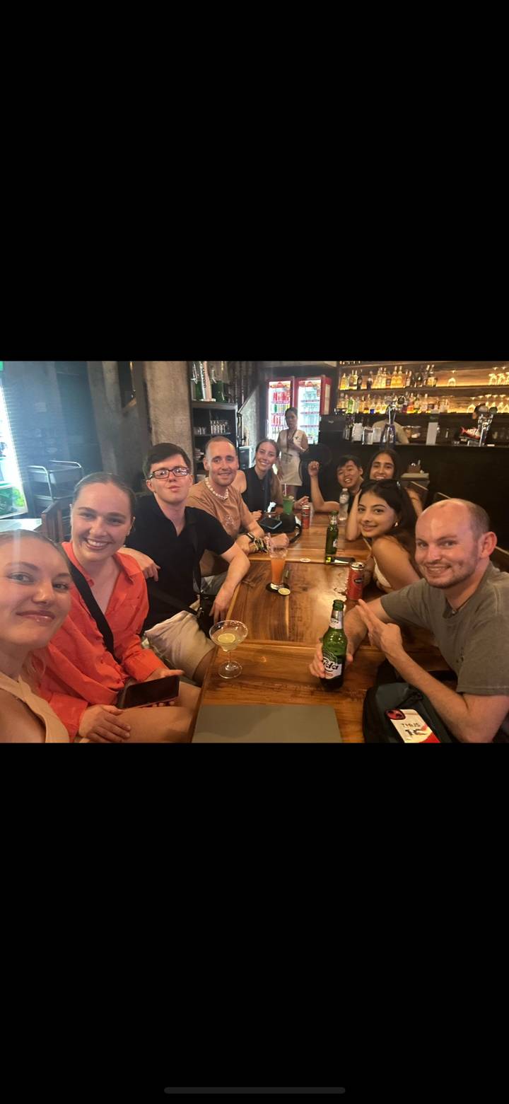 Grupo de personas sentadas alrededor de una mesa con bebidas en un bar