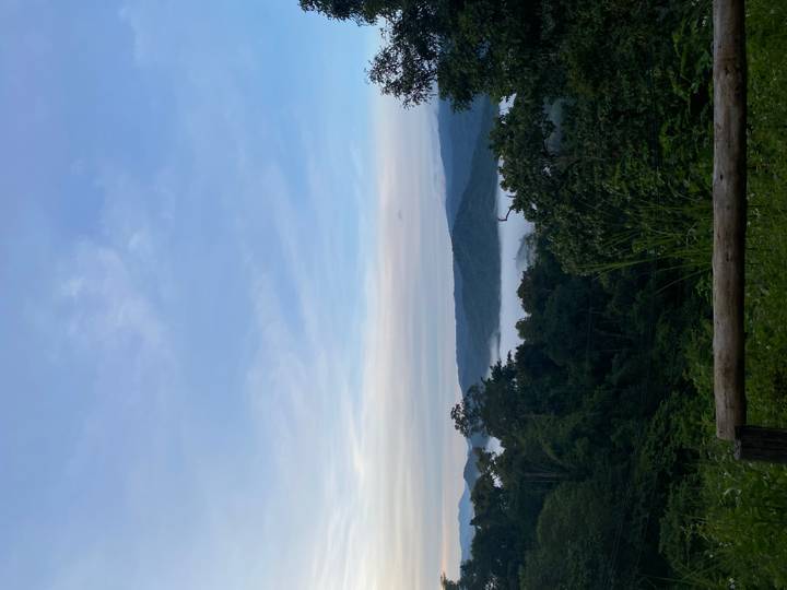 Vista panorámica de montañas y bosque con nubes al amanecer.