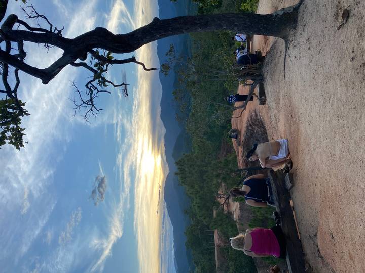 Personas sentadas en un mirador escénico viendo el atardecer.