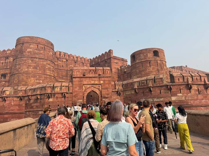 Multitud entrando por la puerta arqueada de un fuerte histórico.