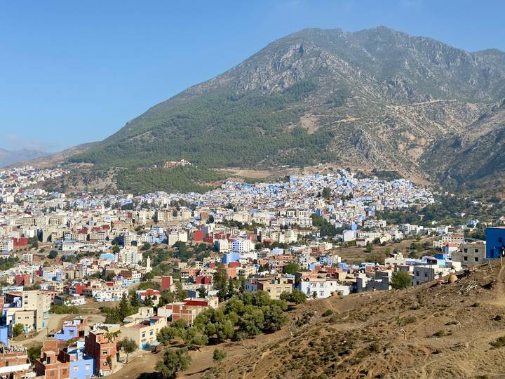 Vista de Chefchaouen con edificios pintados de azul enclavados contra una montaña.