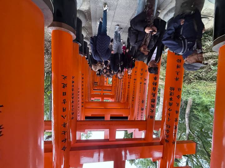 Tourists walking through a torii gate path at Fushimi Inari Shrine.