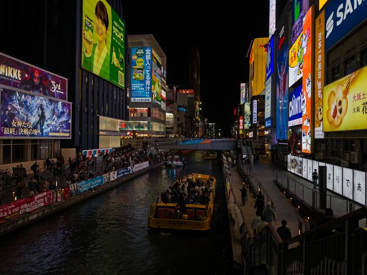 Busy street scene with illuminated signs and a canal.