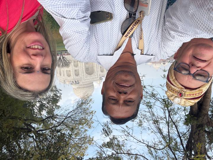 Three people taking a selfie with the Taj Mahal in the background.