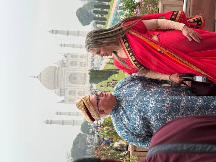 Two people in traditional attire with the Taj Mahal in the background.