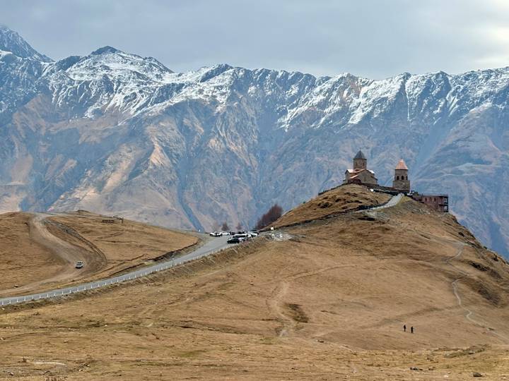 Iglesia en la cima de la colina con montañas nevadas al fondo.