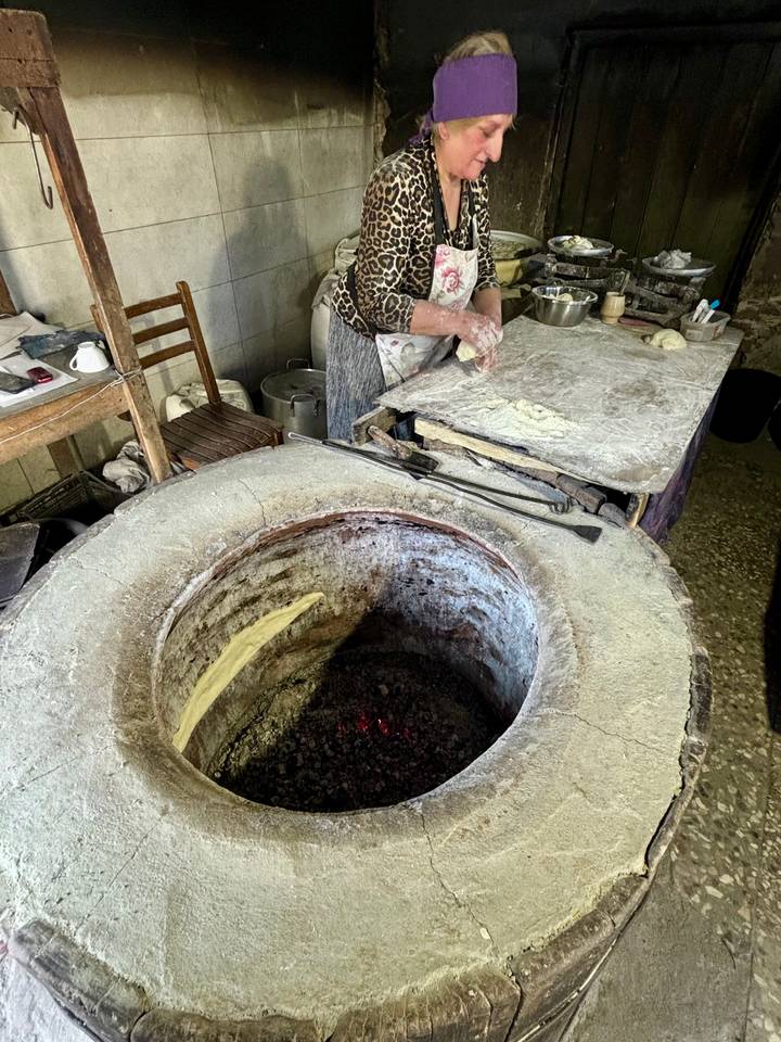 Una persona horneando pan plano tradicional en un tono.