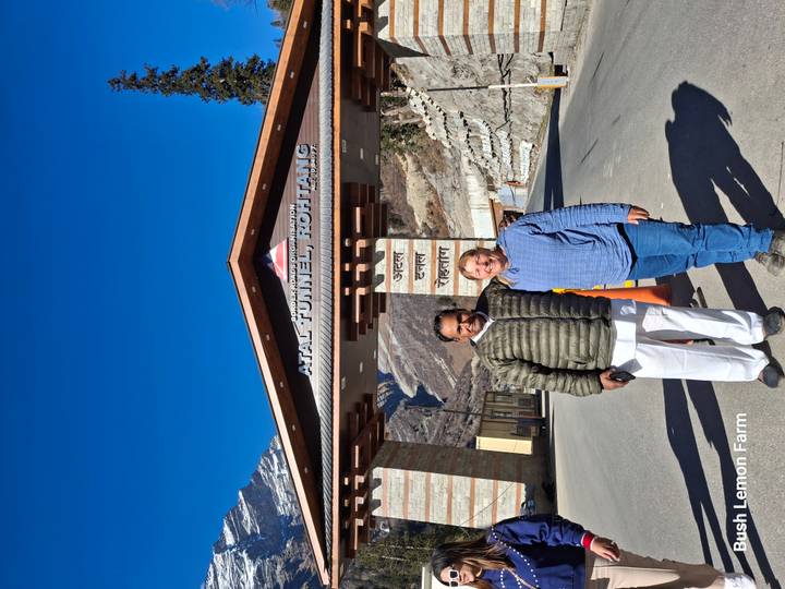 Two people standing at the entrance of the Atal Tunnel with mountains in the background.
