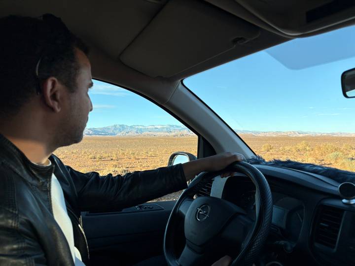 Homme conduisant à travers un paysage désertique.