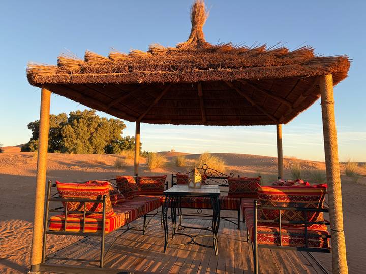 Gazebo dans le désert avec sièges et décoration traditionnels.