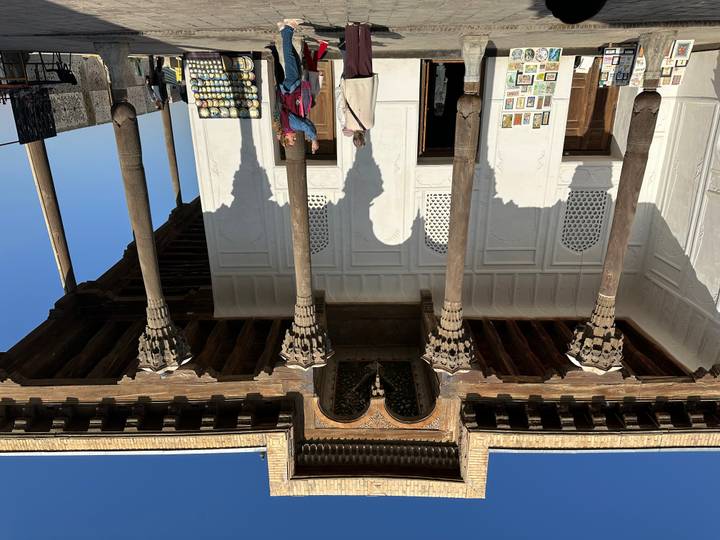 Un gran salón con pilares de madera con personas observando.