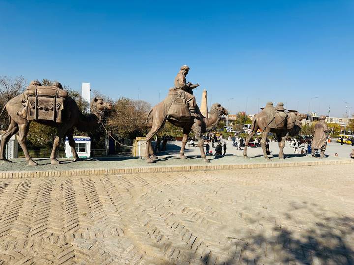 Una escultura de camellos y personas en un día soleado.