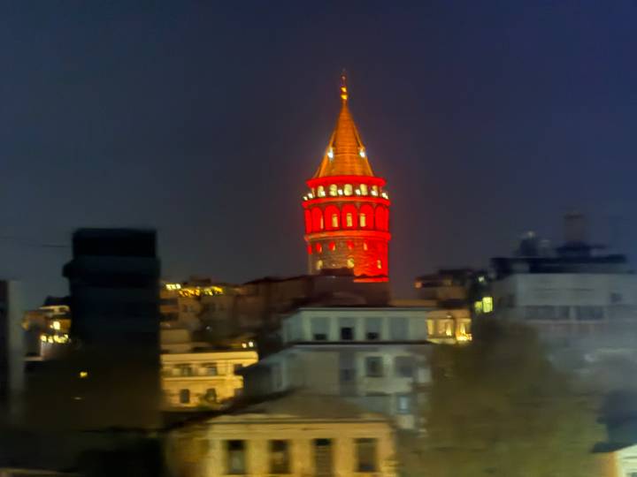 Ein hell erleuchteter Turm über einer nächtlichen Stadtlandschaft.