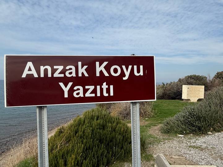 Ein Schild mit der Aufschrift 'Anzak Koyu Yazıtı' mit einem Denkmal.