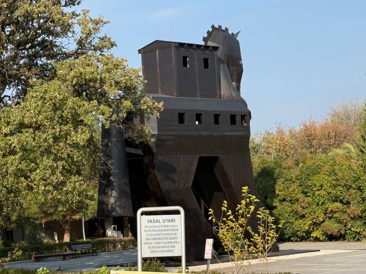 Hölzernes Trojanisches Pferd mit Grünzeug drumherum.