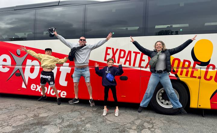 Familie springt vor einem 'Expat Explore' Bus.