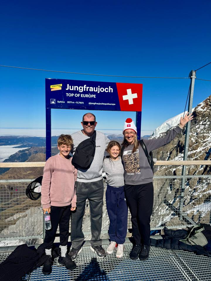 Familie posiert am Jungfraujoch mit Bergen im Hintergrund.