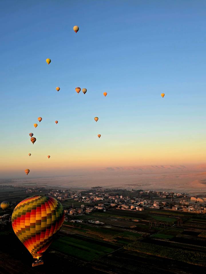 Globos aerostáticos flotando sobre un paisaje brumoso.