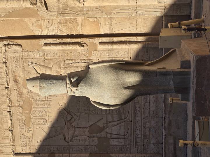 Estatua de un halcón en el entorno de un templo antiguo.