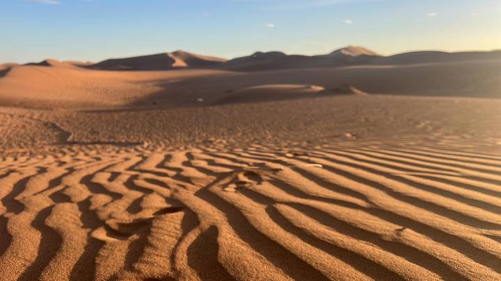 Sand dunes in a desert landscape with rippled sand patterns.