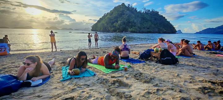Menschen an einem Strand entspannen sich und genießen den Sonnenuntergang.