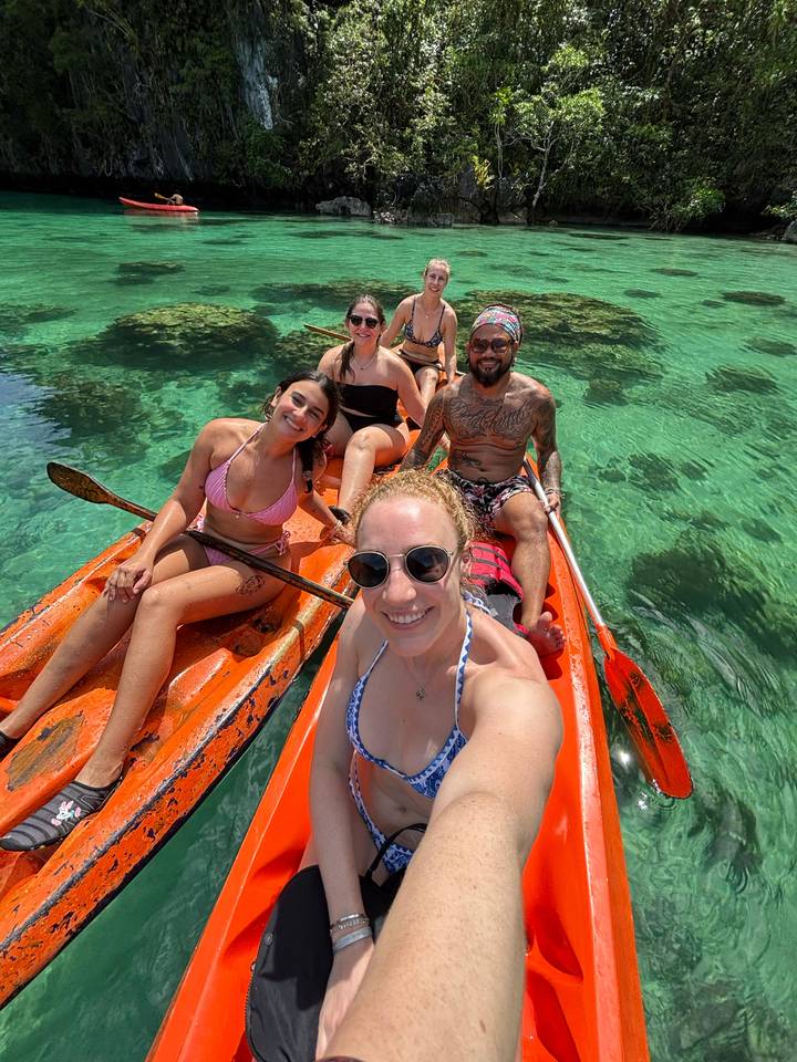 Fünf Personen in Kajaks auf klarem blauem Wasser.