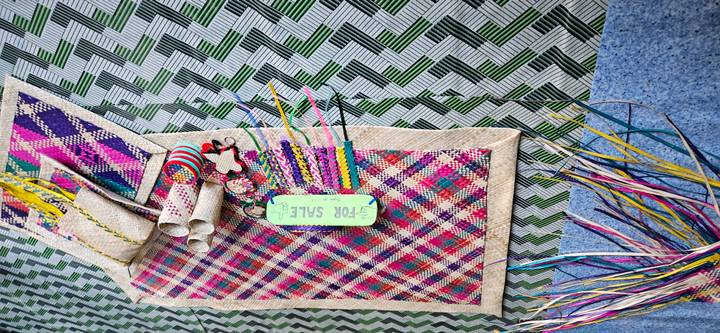 Kleurrijke geweven matten en handwerken uitgestald voor verkoop.