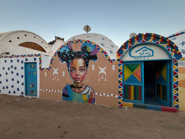 Kleurrijke muurschildering op een muur buiten een hotel.