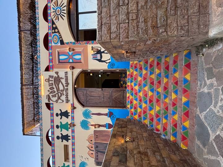 Kleurrijke restaurantingang met geschilderde muurdecoraties.