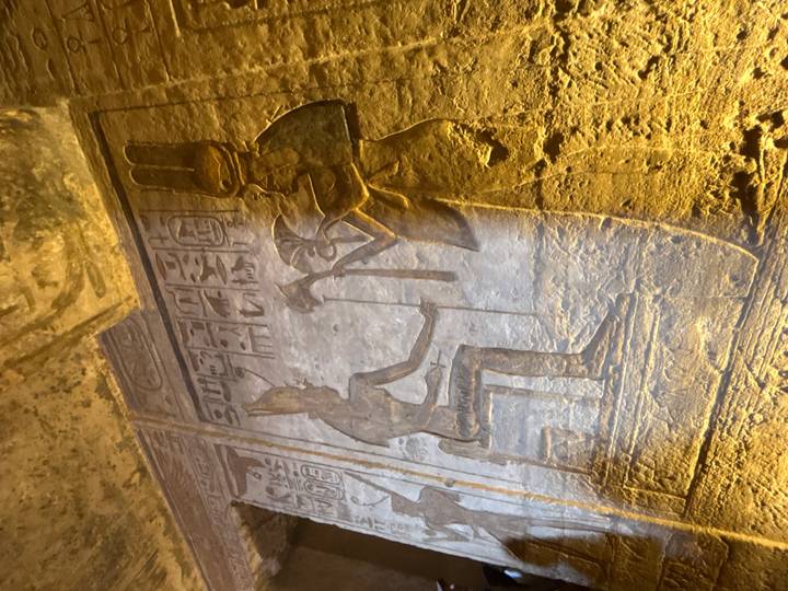 Oude gravures op een tempelmuur die figuren en symbolen tonen.