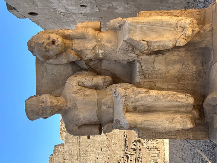 Verweerde standbeelden van oude Egyptische figuren.