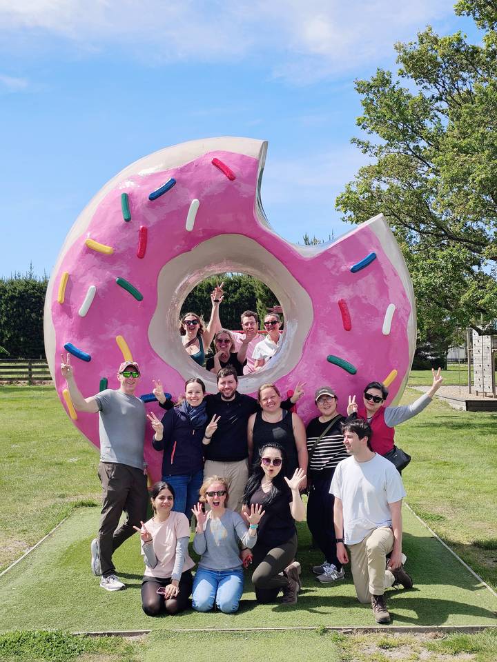 Groep mensen poseren met een groot donutbeeldhouwwerk