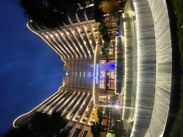 Hotel moderno de torres gemelas con una fuente iluminada por la noche.
