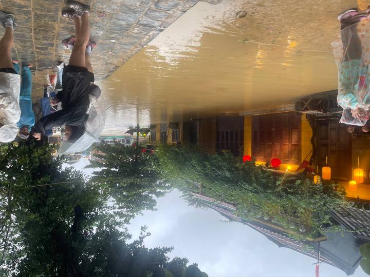 Calle inundada con personas en impermeables y paraguas.