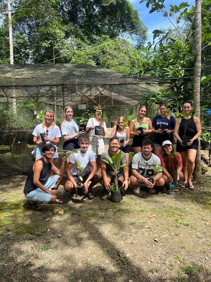 Gruppe von Menschen, die kleine Pflanzen in einer Gartenumgebung halten
