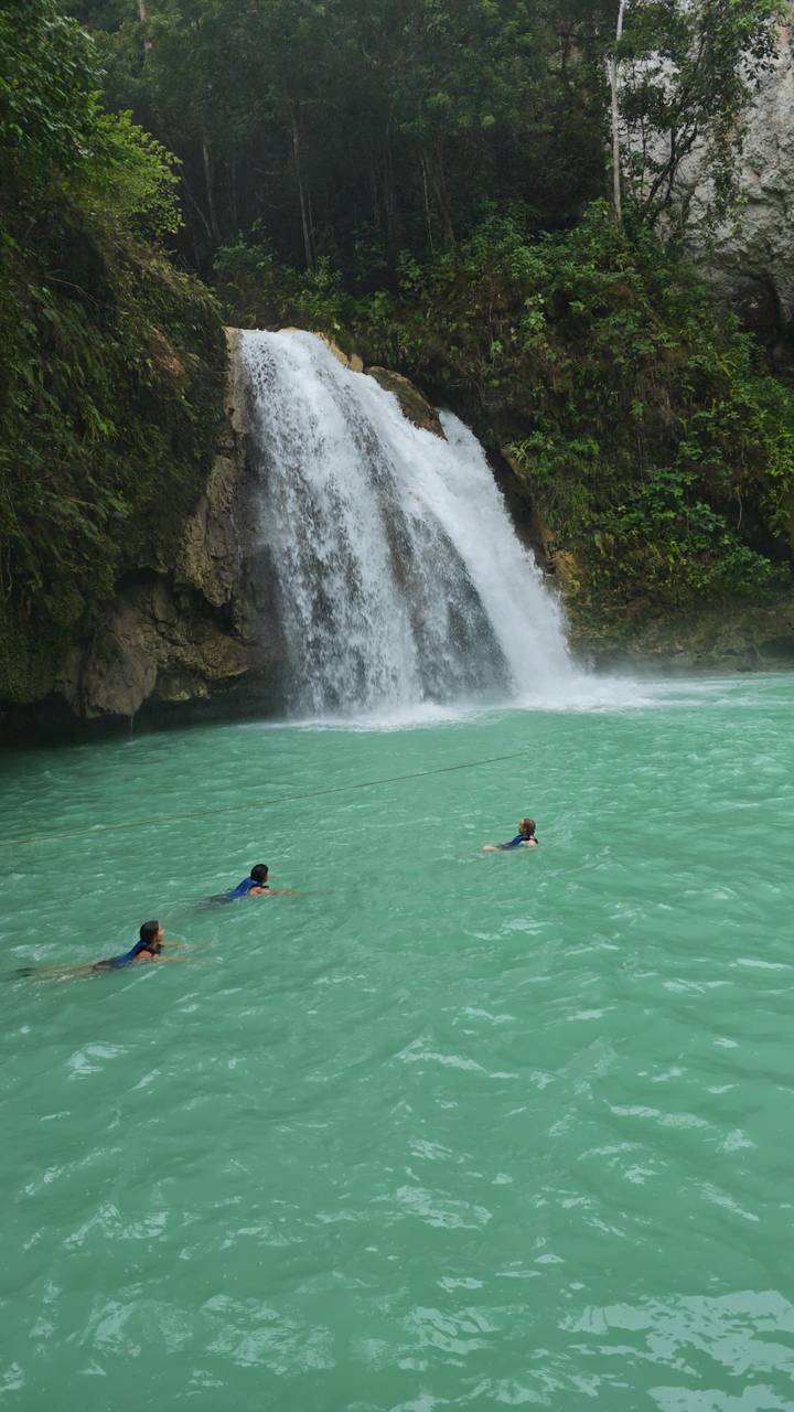 Zwei Personen schwimmen in der Nähe eines Wasserfalls